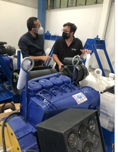 Dos técnicos de Rasa Motores revisan un motor diesel montado sobre una unidad de manejo de fluidos en taller